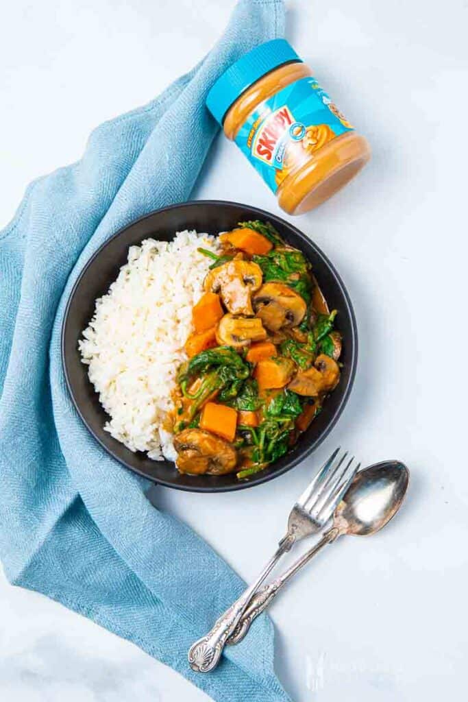 Plate of sweet potato curry and white rice with a jar of peanut butter