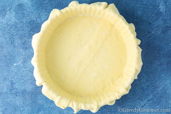 Lining a tin with puff pastry.