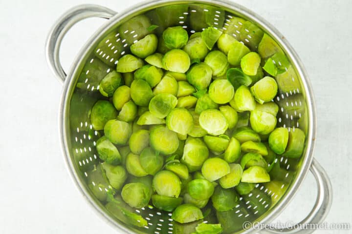 Parboiled brussels sprouts in a colander.