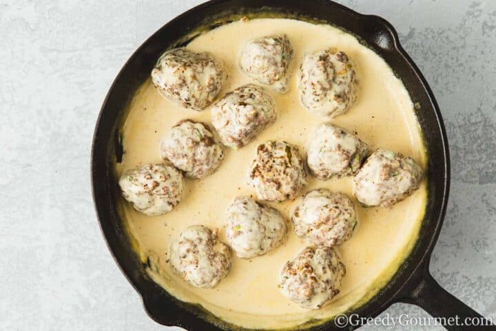 Lamb meatballs in sauce in a pan.