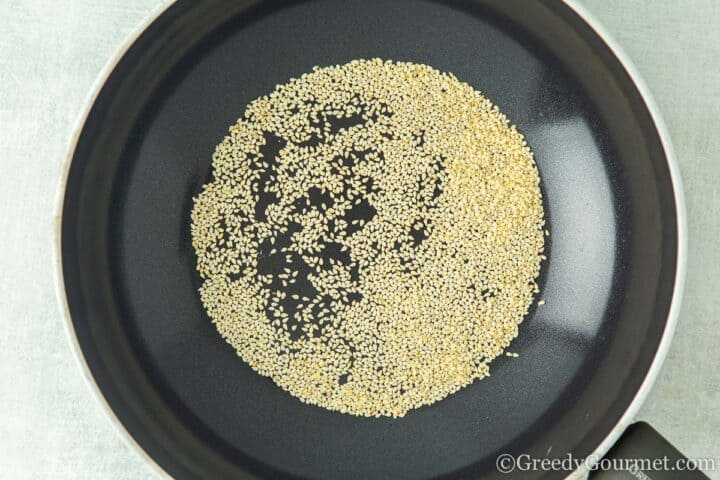 toasting sesame seeds in a frying pan.