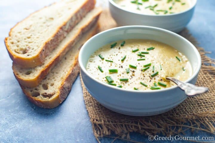 Potato fennel soup served in bowls next to slices of bread.