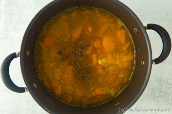 pot with stock, spices, carrots and onions.