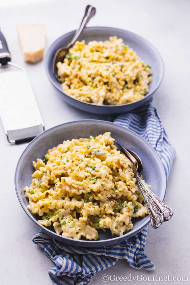 gorgonzola pasta in a blue bowl with fork and spoon.