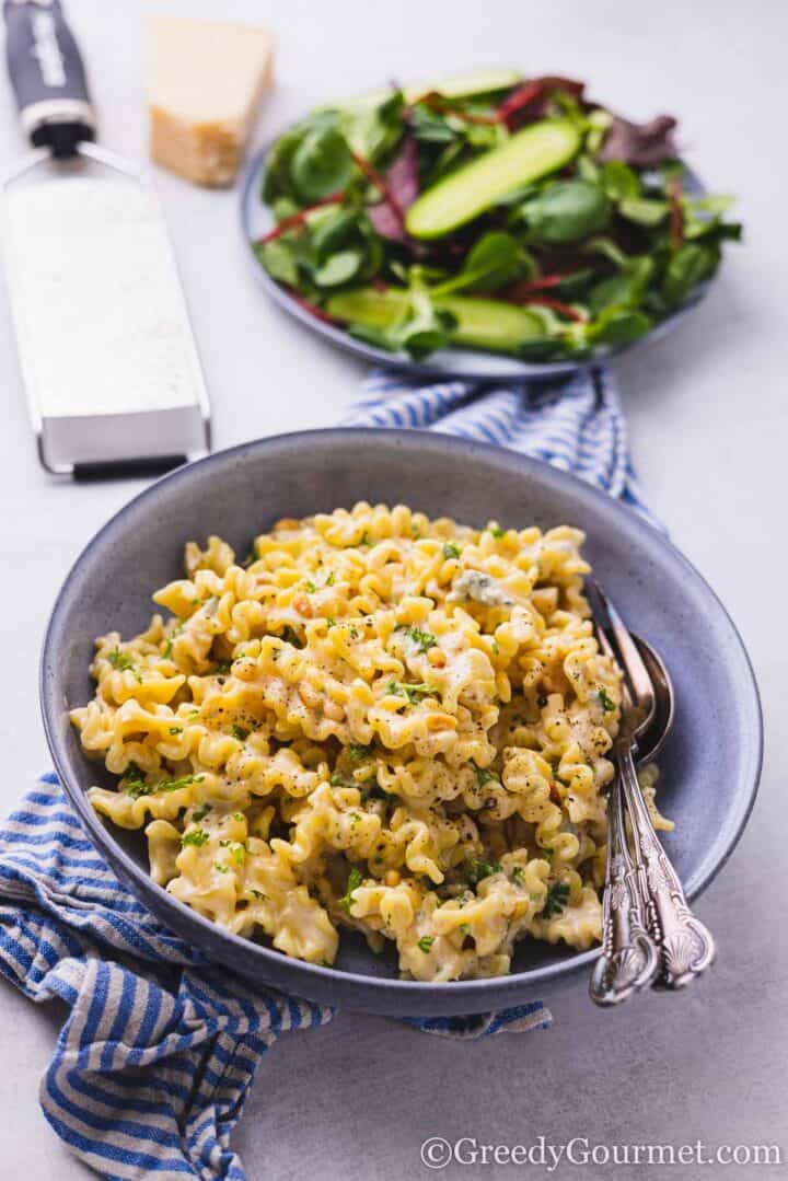 pasta in a blue bowl with a salad side dish.