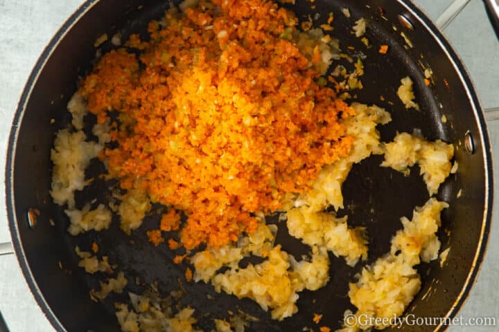 adding chopped carrots to a pan.