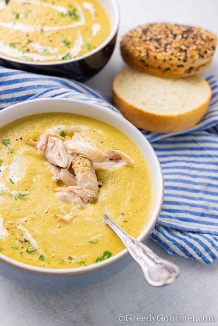 Bowl of chicken carcass soup with slices of bread.