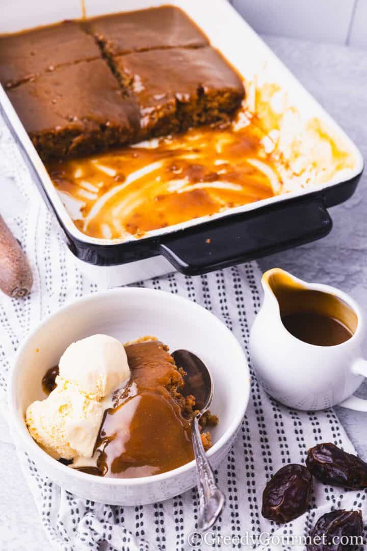 Sticky Toffee Pudding served in a bowl with ice cream.