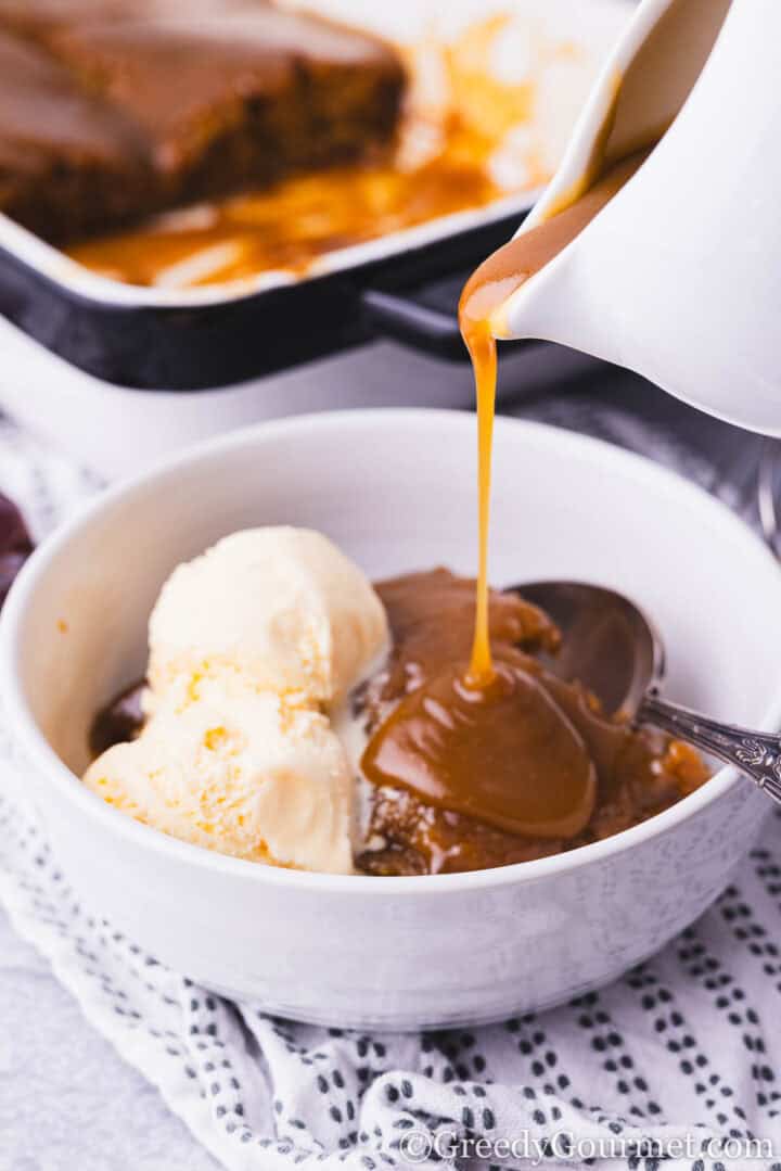 Sticky Toffee Pudding served in a bowl with ice cream.