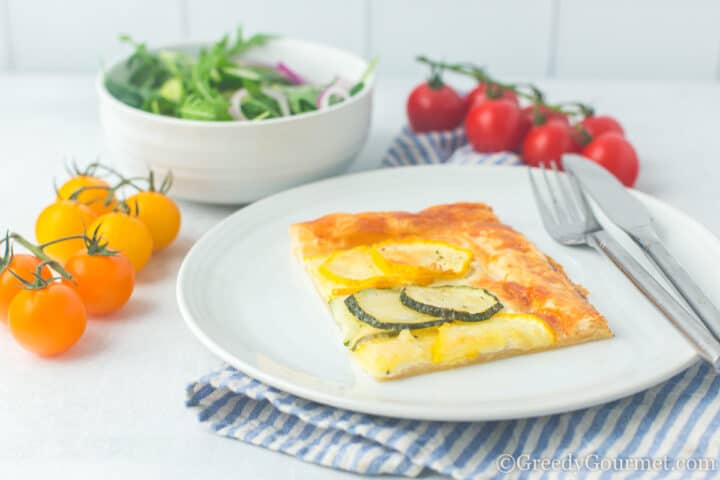 baked tart with tomatoes and salad on a plate.