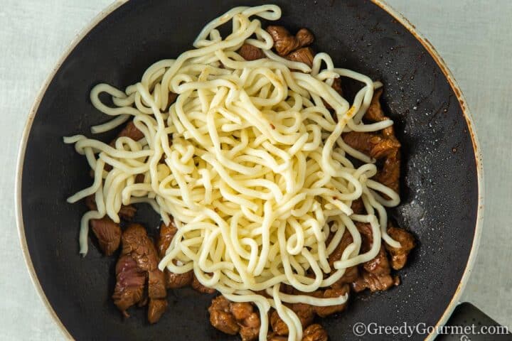 adding noodles to wok.