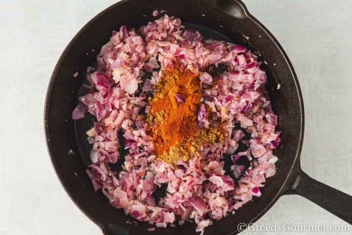 Onion with spices frying in a pan.