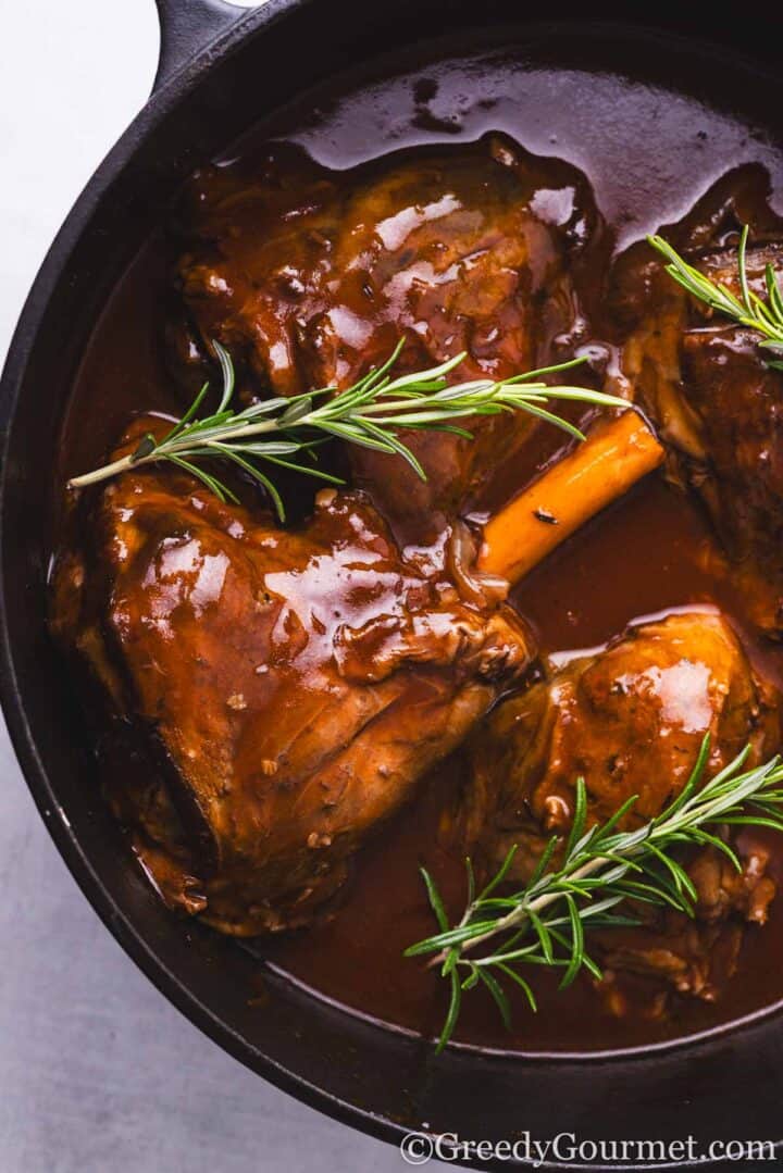 lamb shanks braised in red wine in a pot.