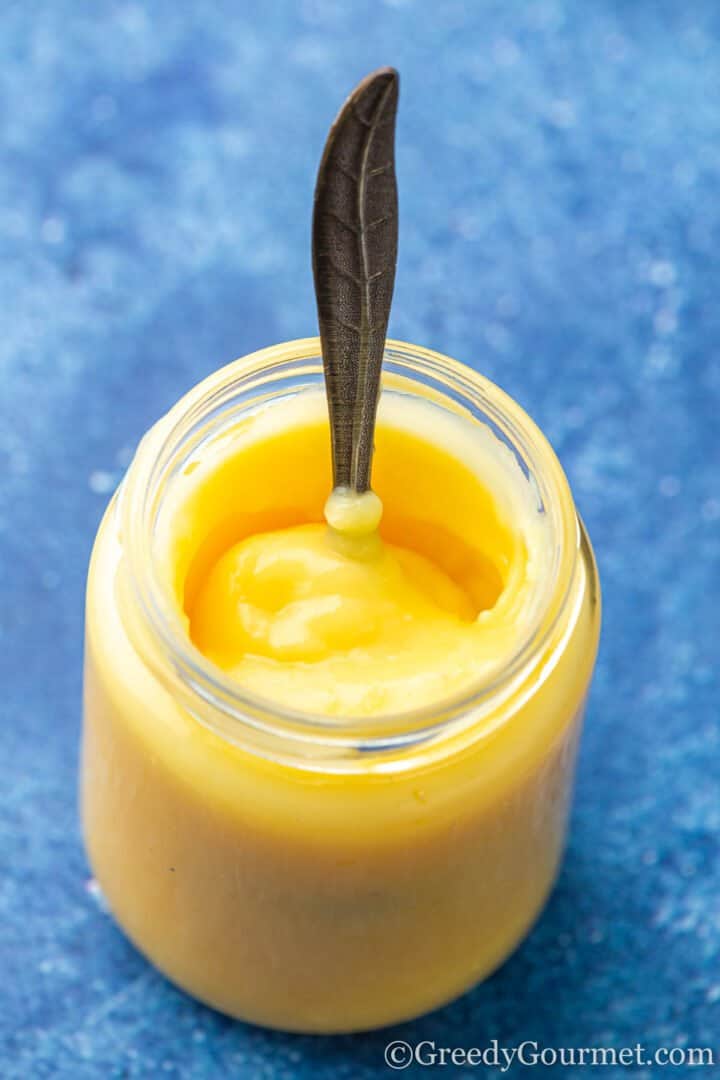 Smooth lemon curd in a glass jar.