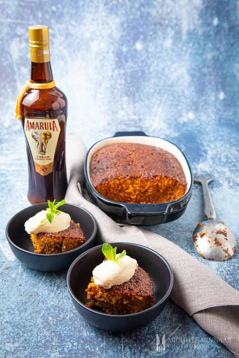 Malva Pudding in a casserole dish with a bottle of amarula 