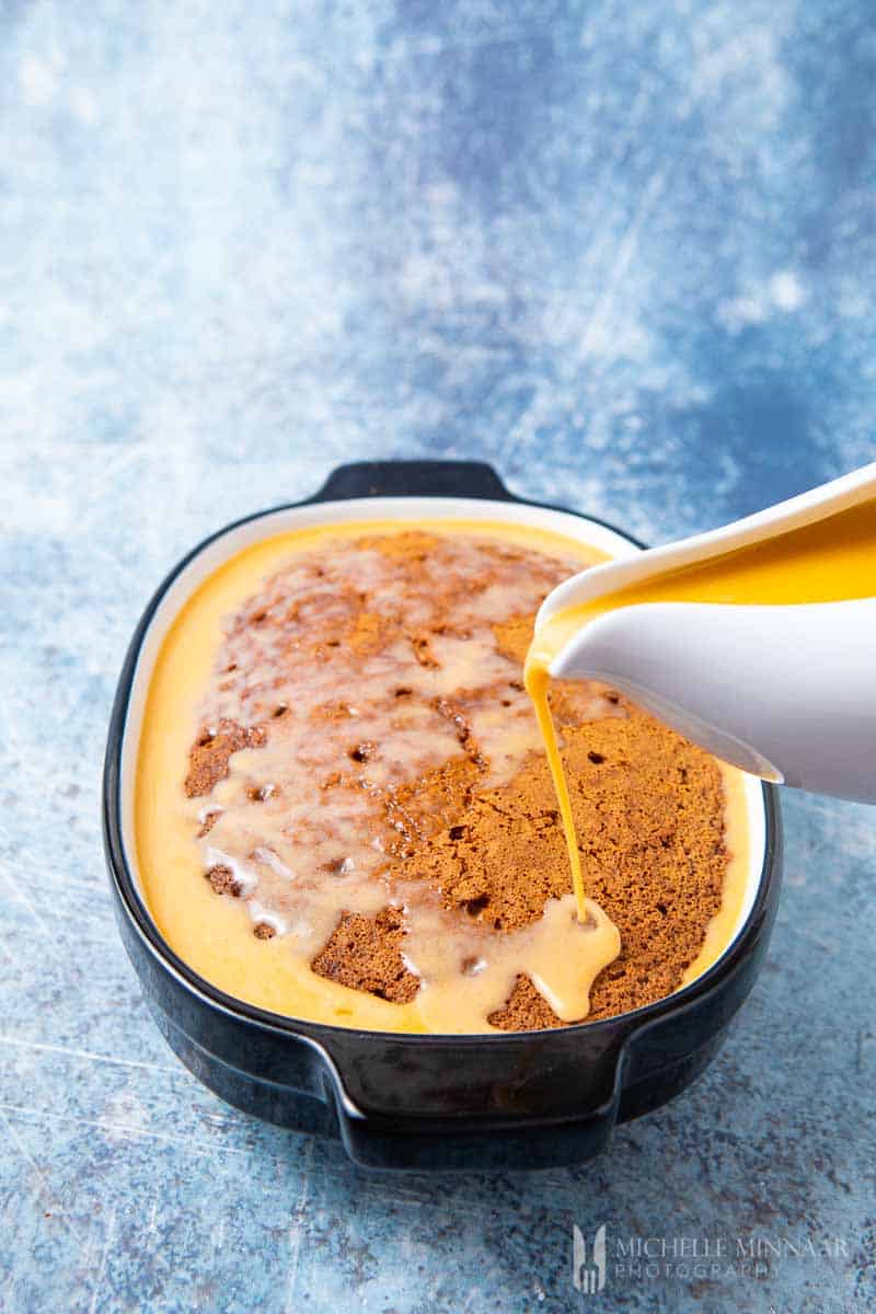 Pouring cream into a Malva Pudding