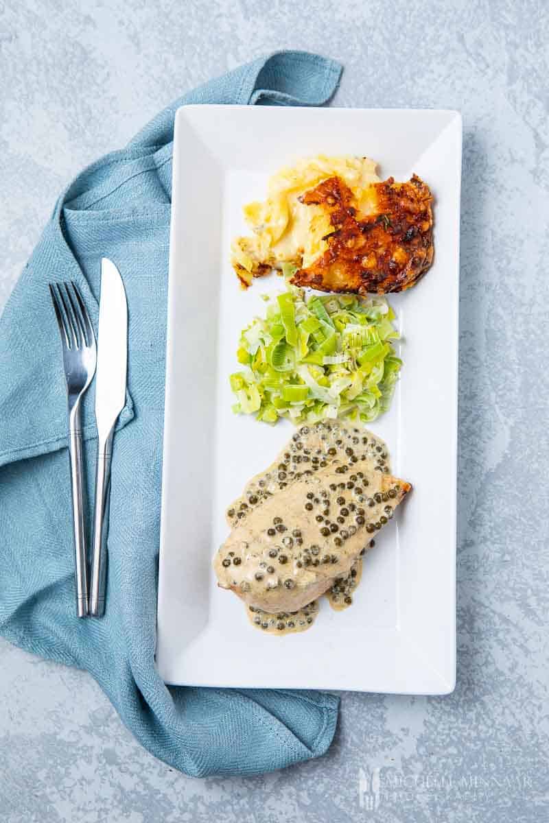 A rectangle plate with chicken, lettuce and a side dish 