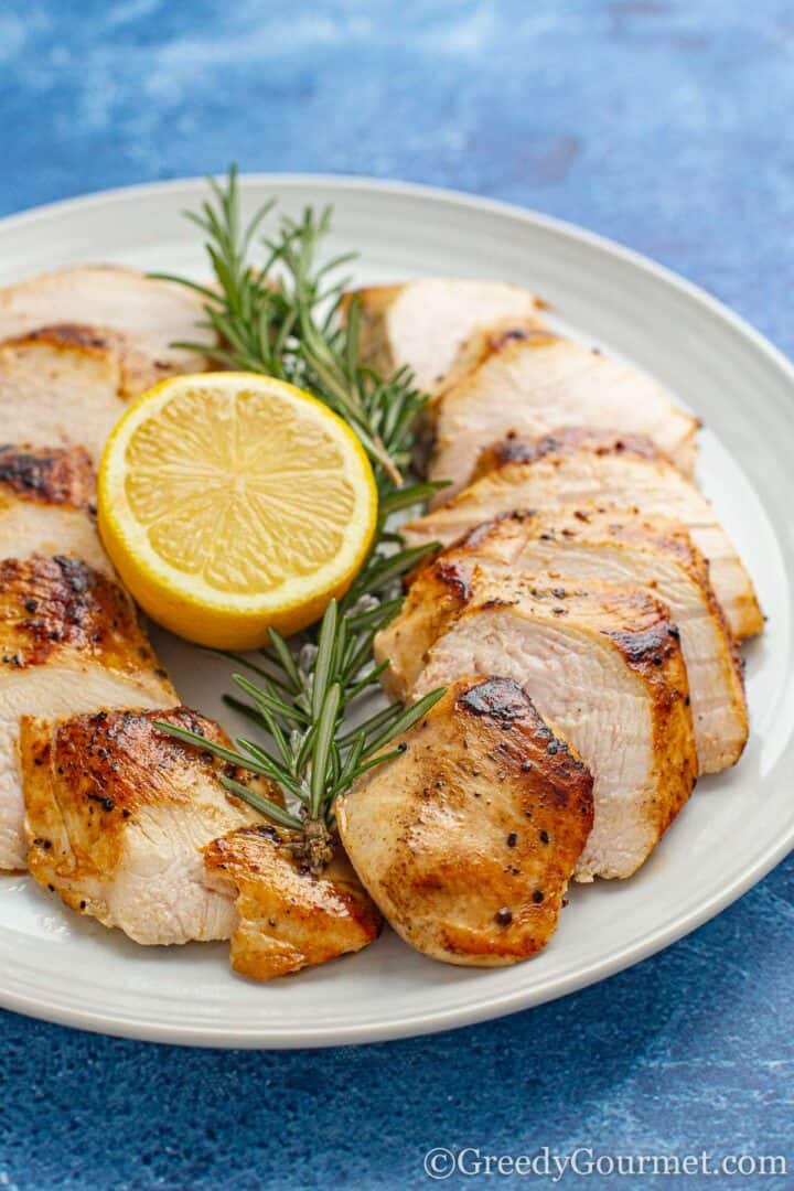 cooked sous vide chicken breast served with lemon and and herbs.