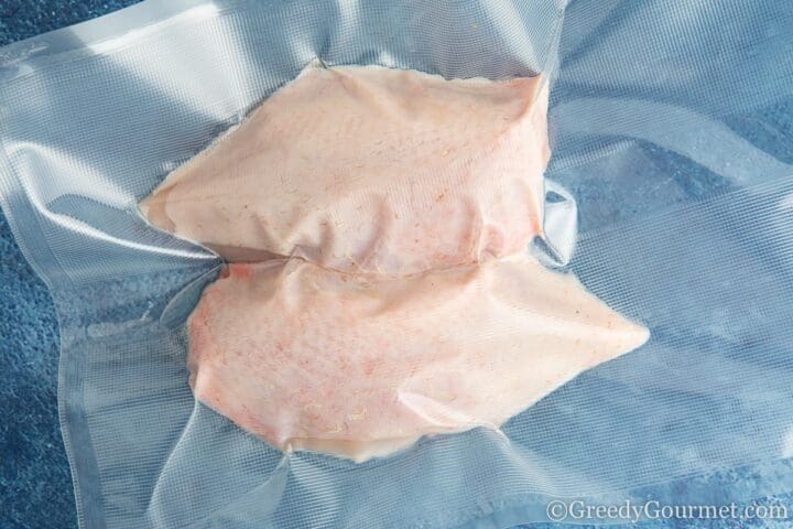 vacuumed chicken breast raw with skin on.