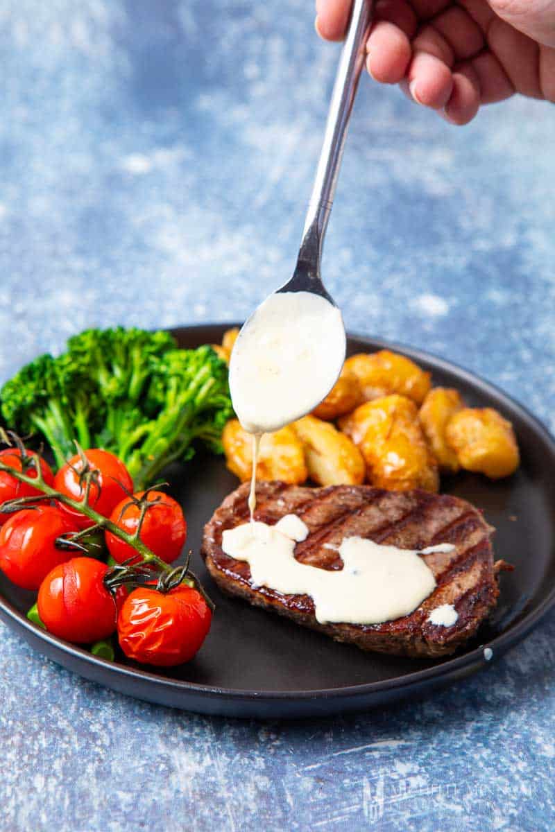 Blue cheese sauce being dripped onto a steak