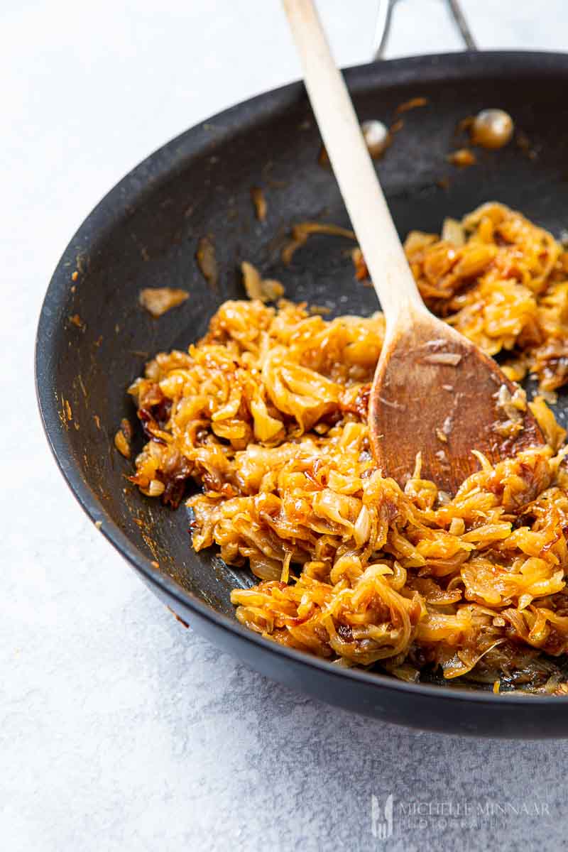 Wooden spoon stirring onions 