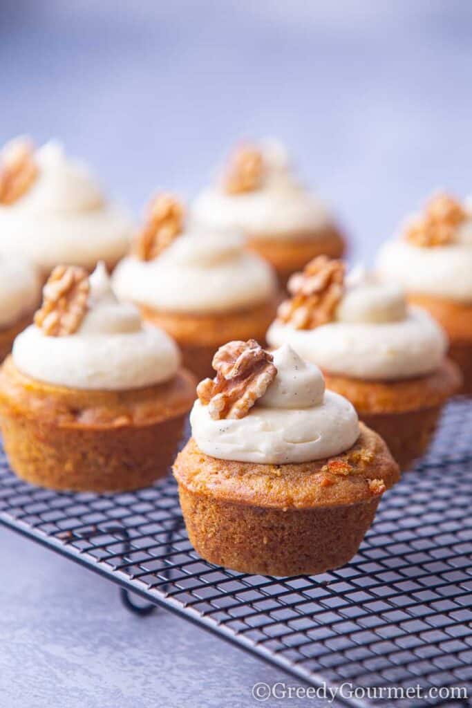 Cupcakes with cream cheese frosting on drying rack