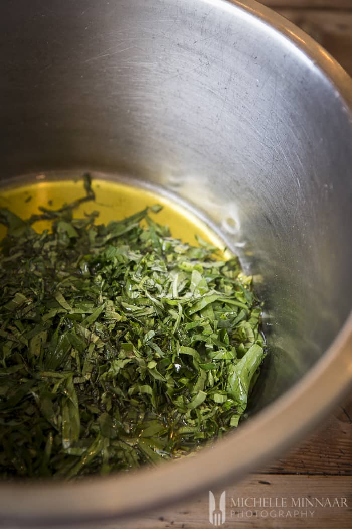 Herbs and oil in a stainless steel bowl