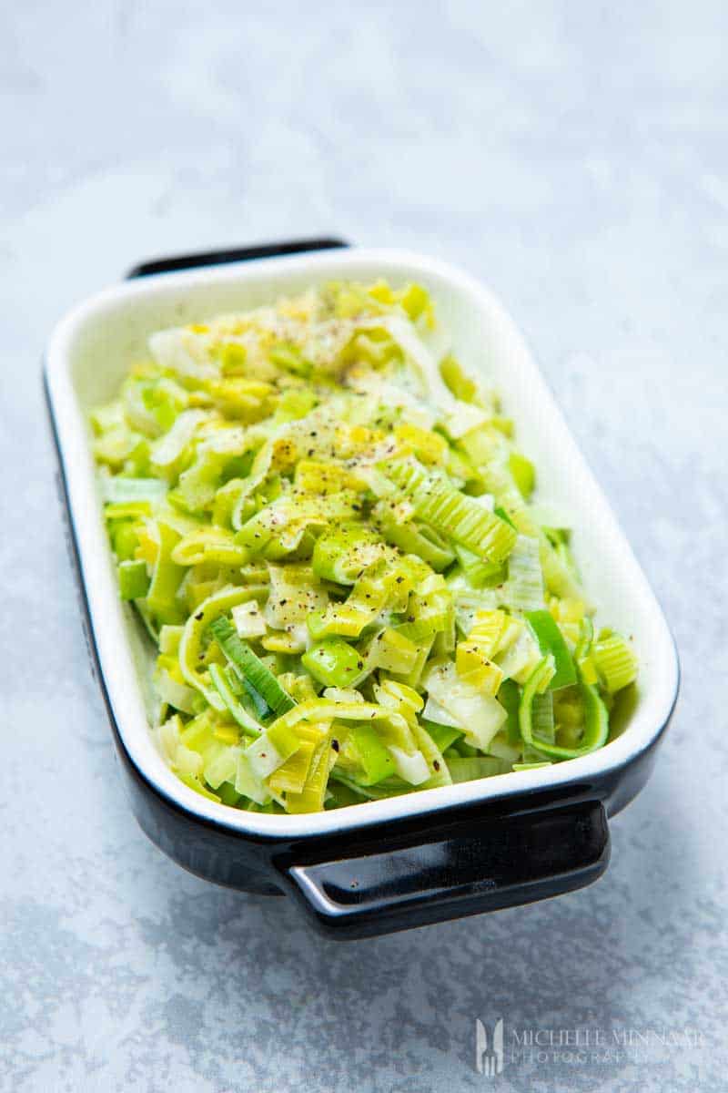 A square casserole dish full of green creamed leeks
