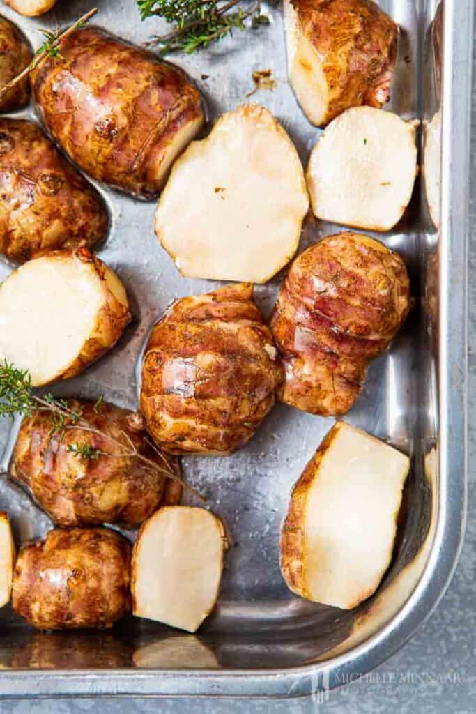 Jerusalem artichokes in roasting tin with oil and thyme