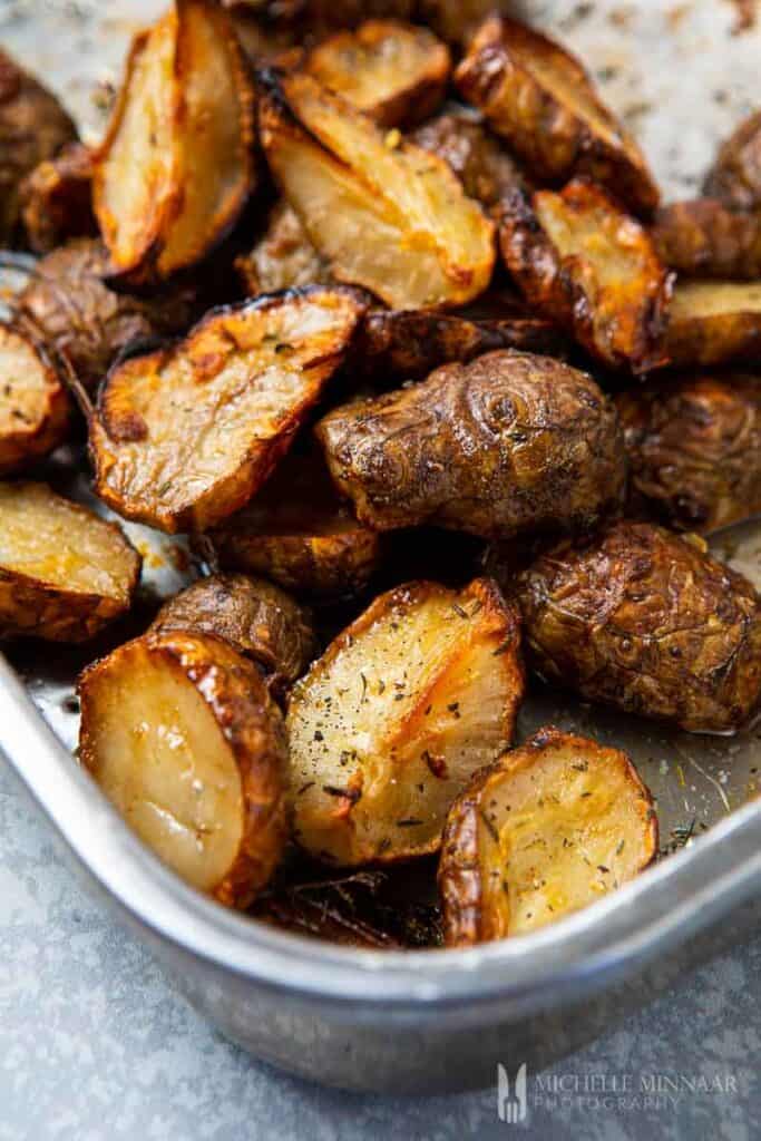 Golden and crispy baked sunchokes in silver roasting tin.