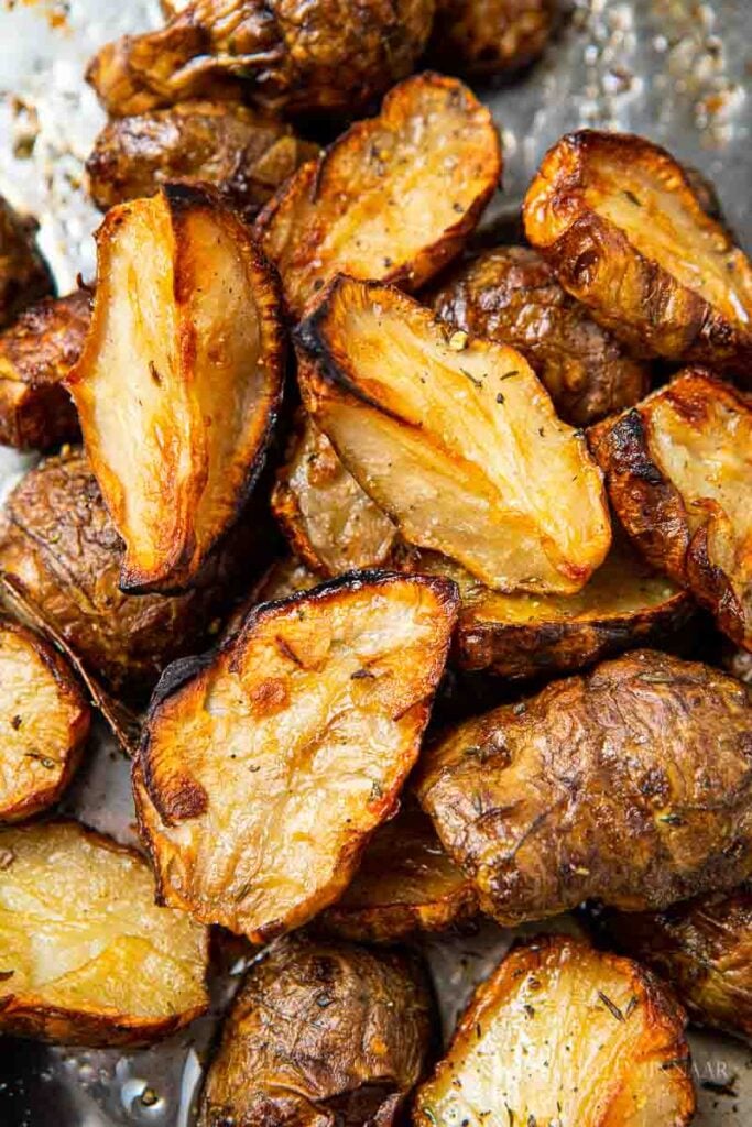 A pile of golden Roasted Jerusalem artichokes in a roasting tin.