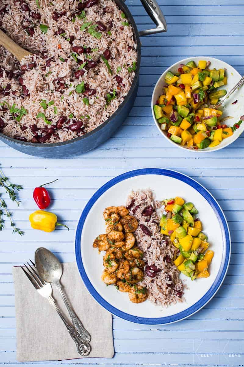 A bowl of rice and peas with a plate of three entrees