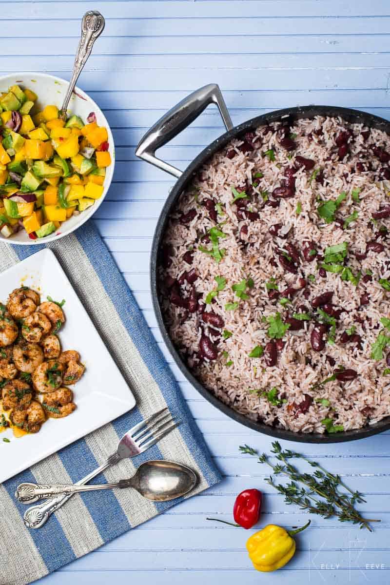 A skillet of rice and peas with a bowl of mango salsa and grilled shrimp