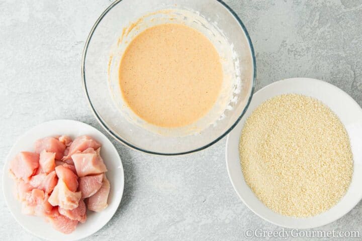 Chicken, breadcrumbs and buttermilk batter on a table.