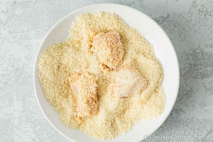 Covering chicken in panko crumbs.