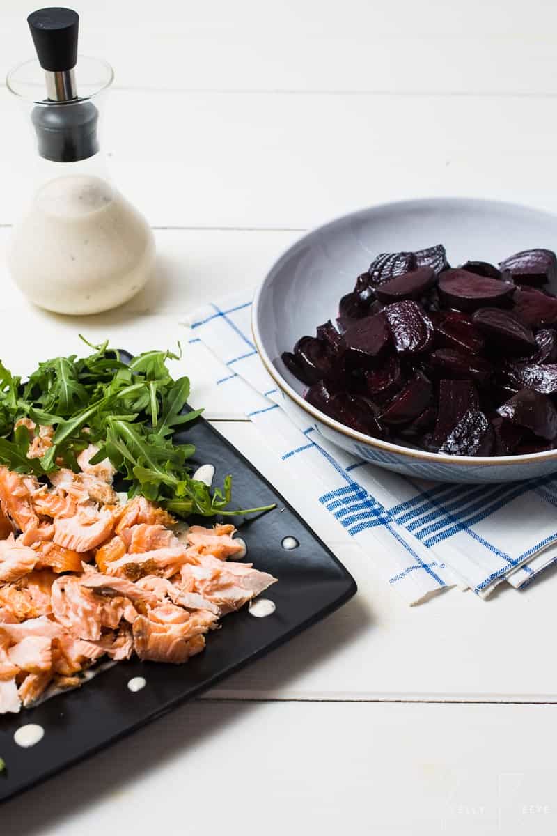 A bowl of roasted beetroot with a salmon and salad on a table 