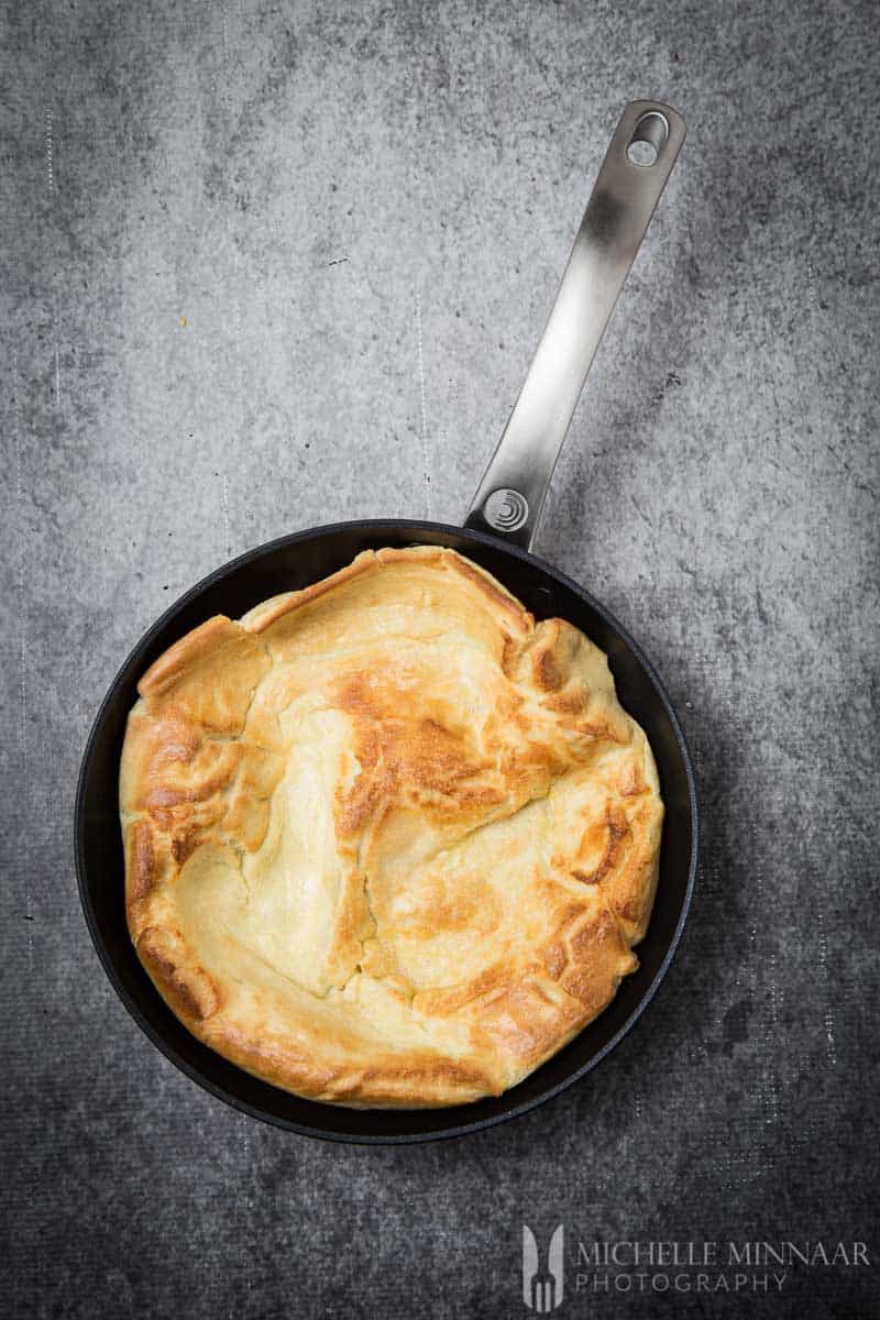A tan colored yorkshire pudding in a saute pan