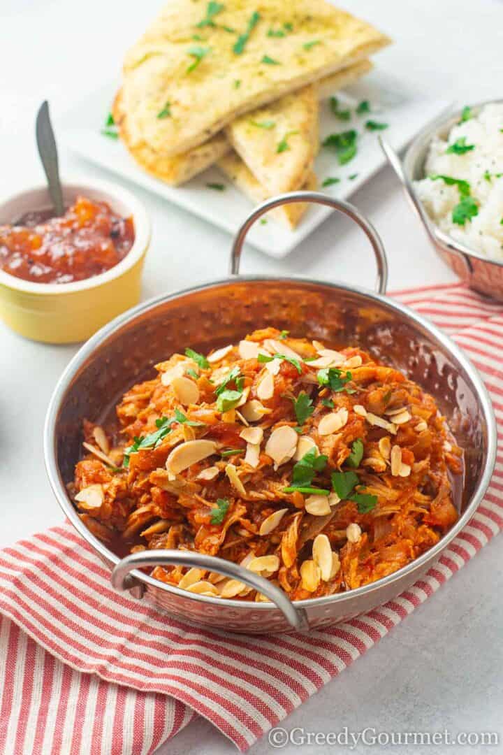 Leftover Turkey Curry in metal bowl with chutney, bread and rice