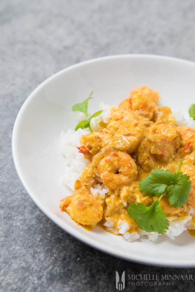 A finished bowl of Prawn Korma, prawns covered in yellow sauce on white rice