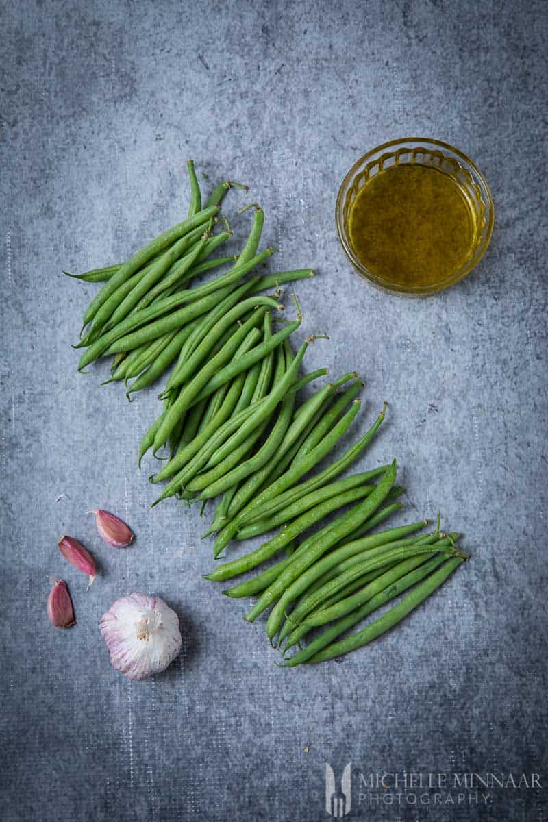 Raw Greenbeans, garlic, oil on a counter