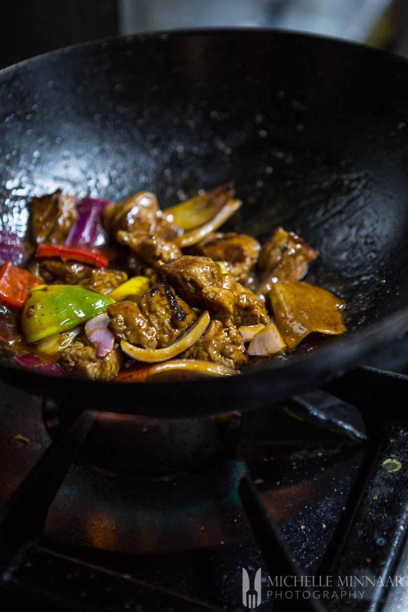 Ingredients for Lomp Saltado cooking in a saucepan