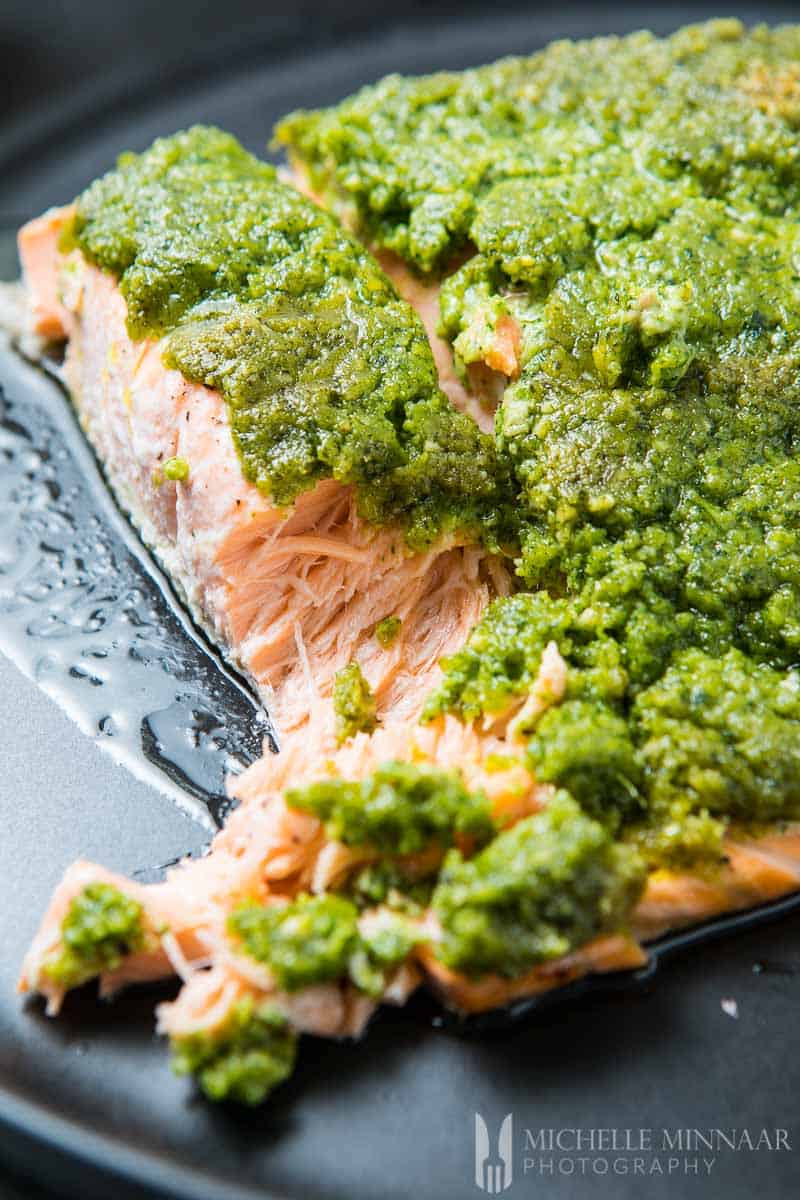 A close up of Salmon covered in pesto green sauce for Pesto Baked Salmon