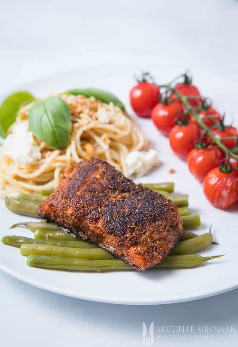 Blackened Cod - A piece of blackended fish on a bed of green beans, with a side of pasta and tomatoes