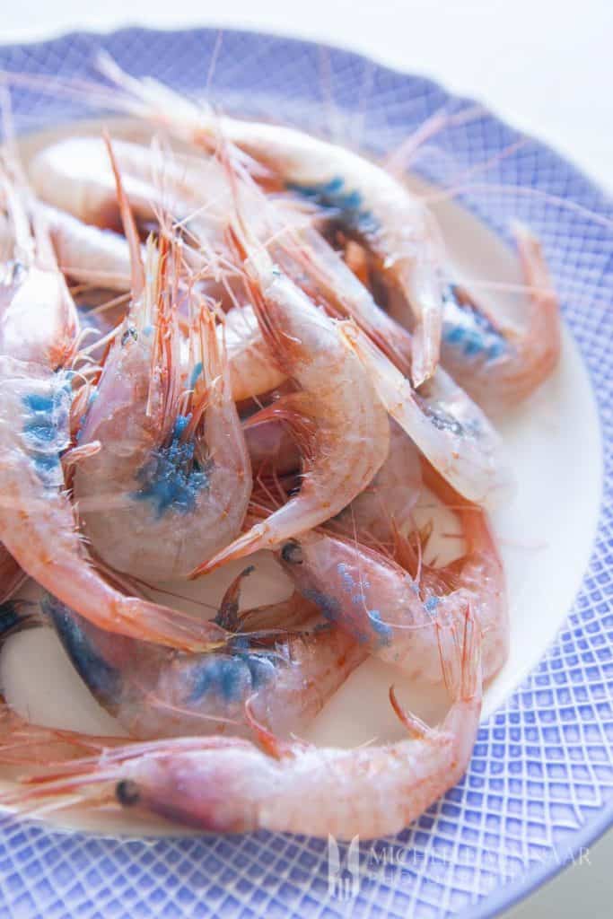 A bunch of raw pink prawns on a blue plate