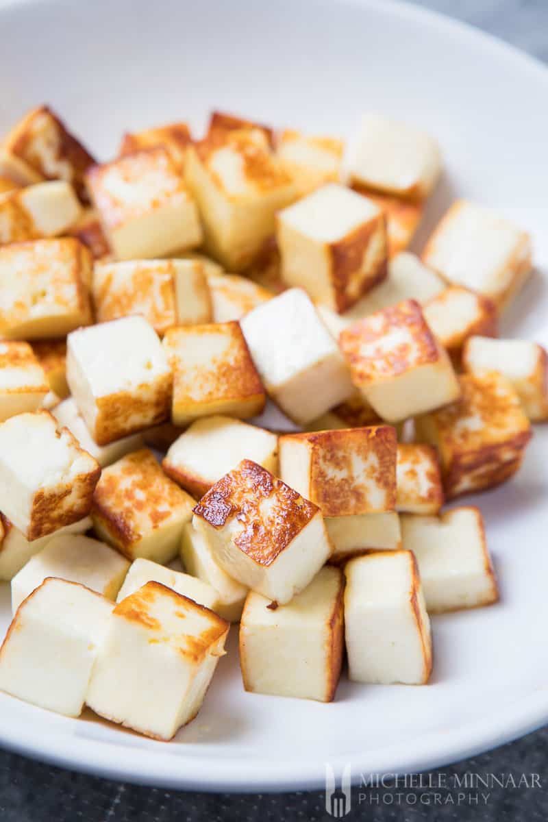 Fried Paneer on a plate, white cubes with brown exterior.