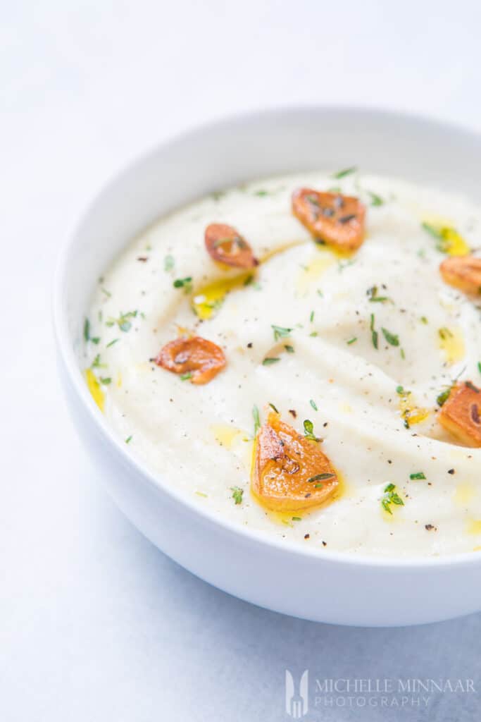 A close up view of a white cauliflower mash with tomato garnish