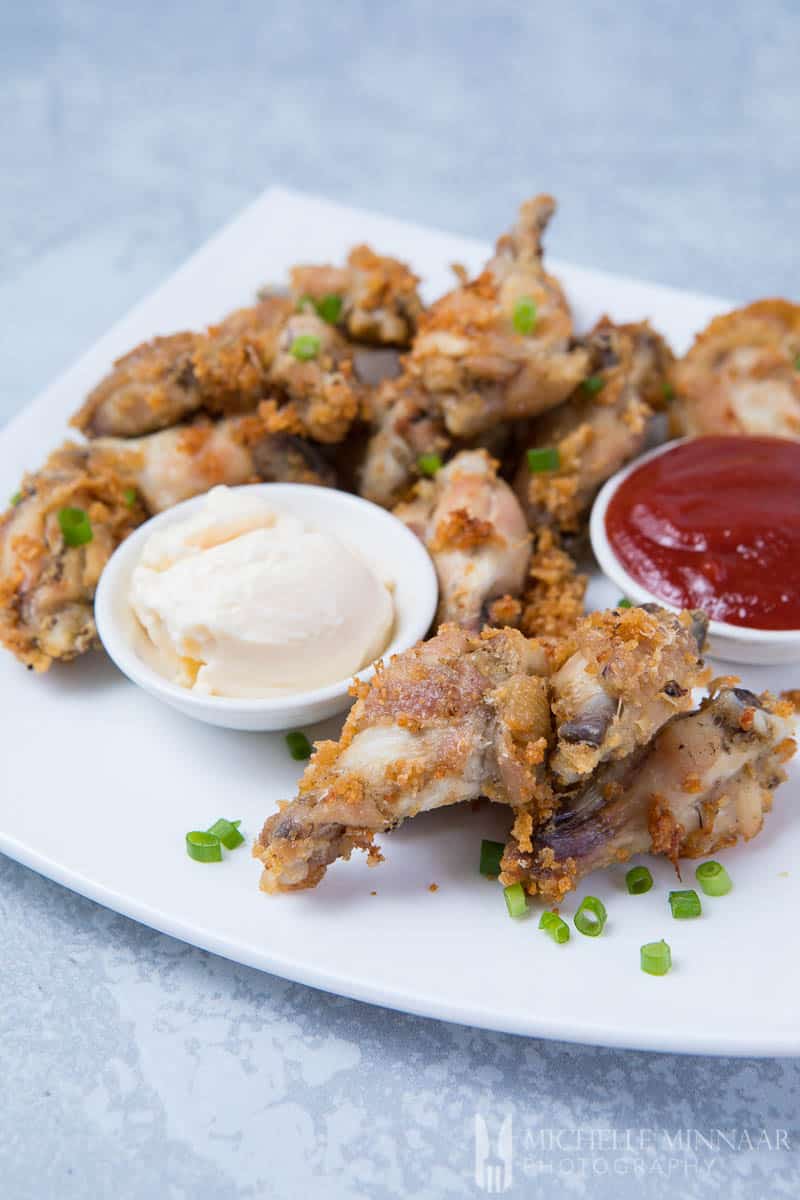 A plate of air fryer chicken wings, browned wings and two sauces