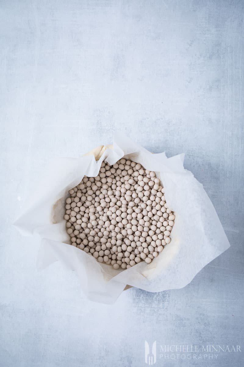 Baking beads inside of a pie shell to make cherry crumble pie