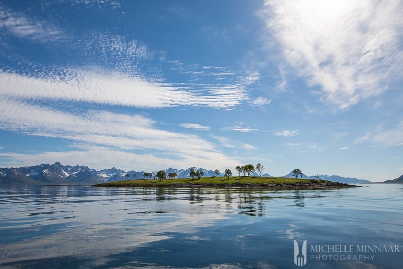 A small green island with mountains in the background