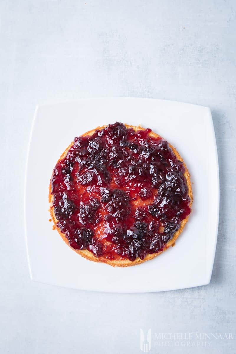 An aerial view of one layer of cake with cherry jam spread on top 